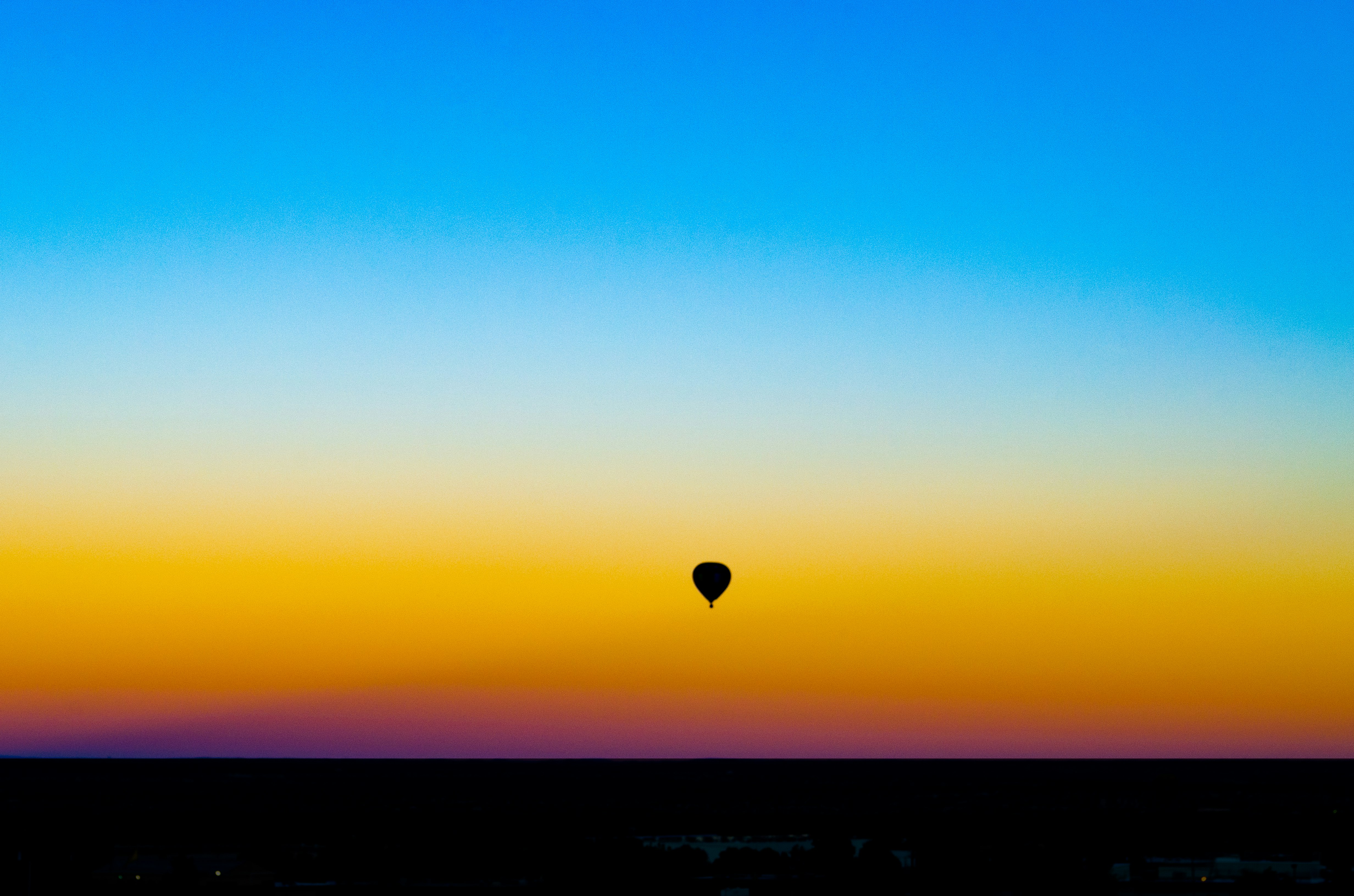 silhouette of hot air balloon under blue sky